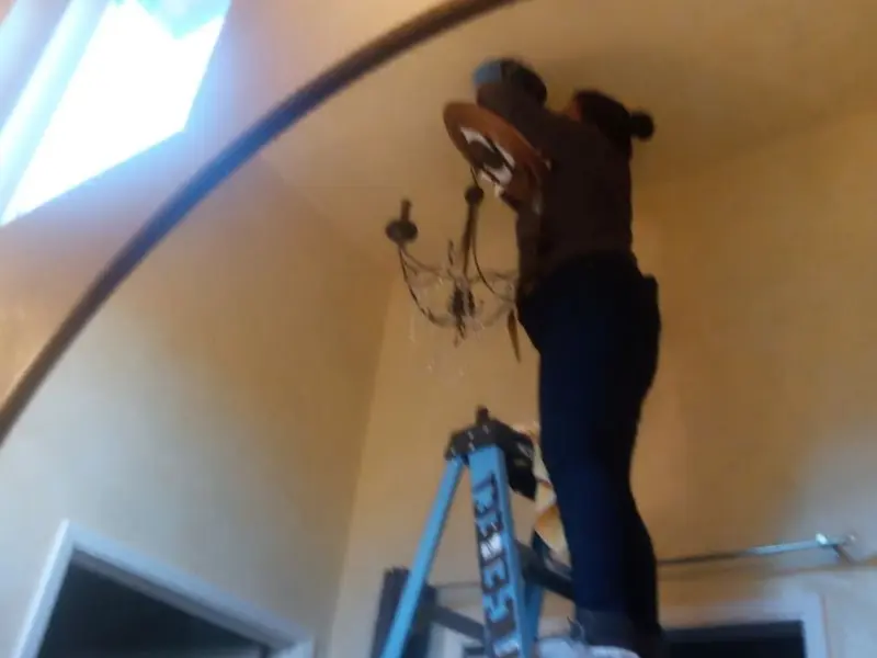 Electrician installing a chandelier in a Gloucester Courthouse residence